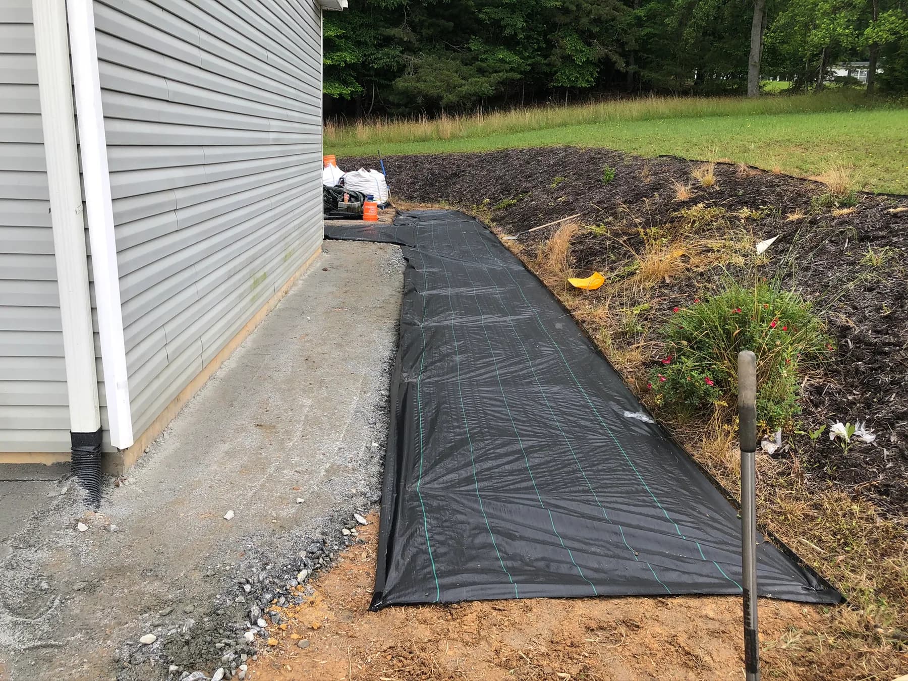 Prepared patio base and fabric layout along a residential foundation, view 2