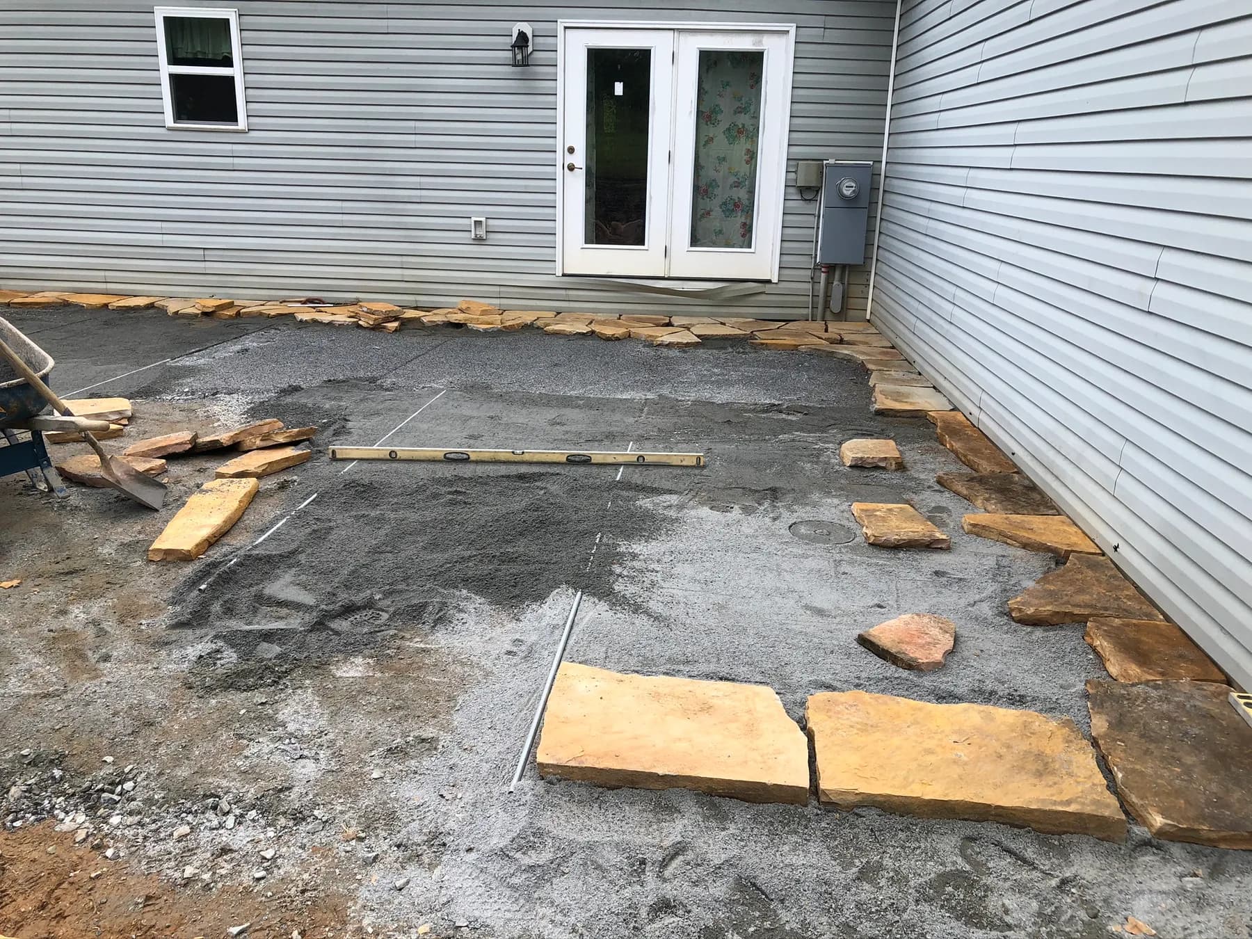 Natural stone patio layout with base preparation and door transition, view 3