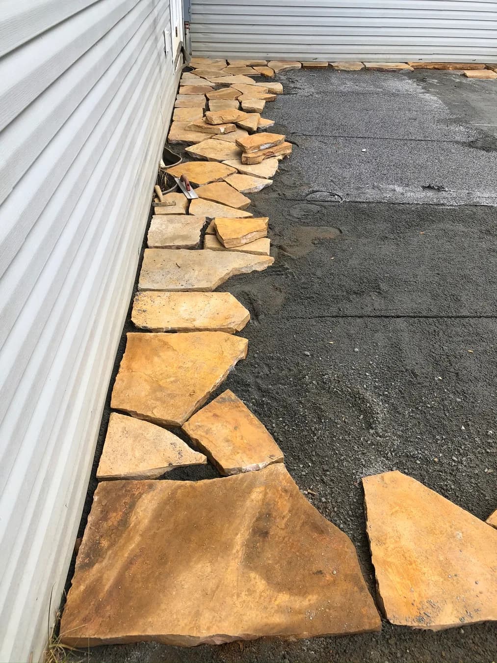 Natural stone edge fitment beside the prepared patio base