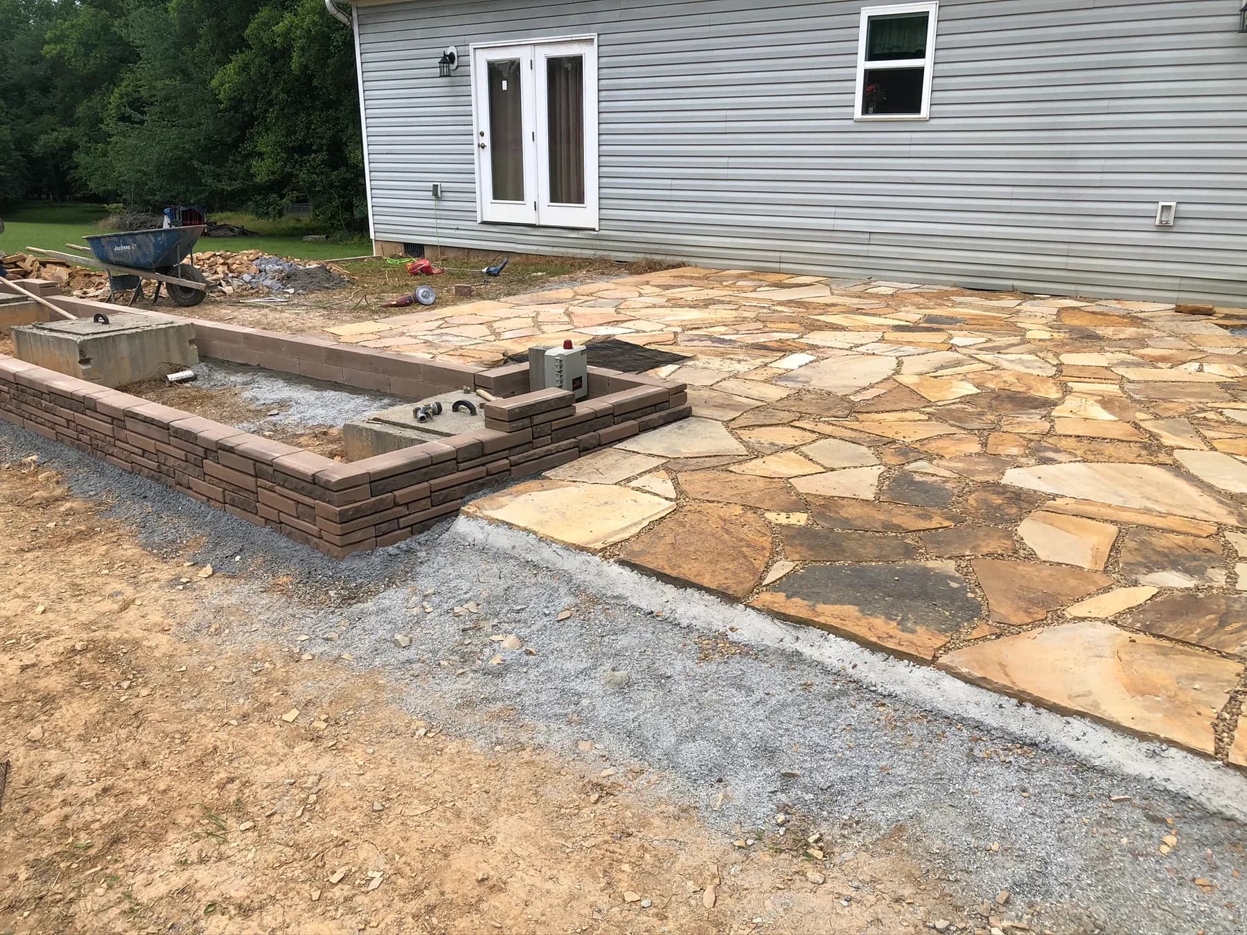 Natural stone patio with step transition and low wall work in progress