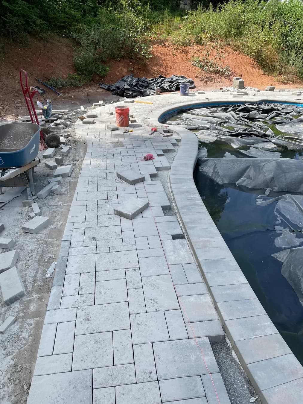 Poolside paver deck installation with border course and curved pool edge, view 8