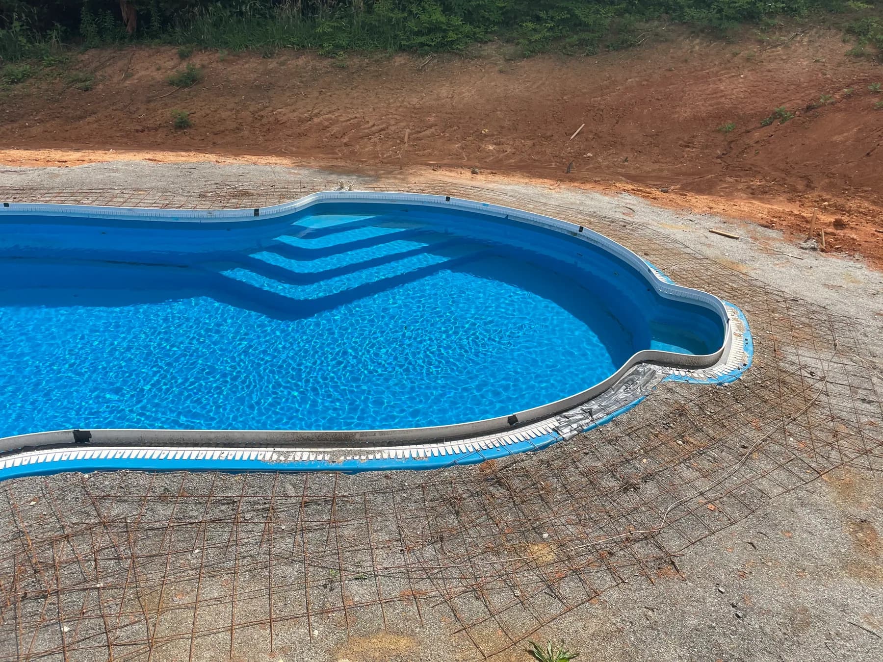 Poolside paver deck installation with border course and curved pool edge, view 1