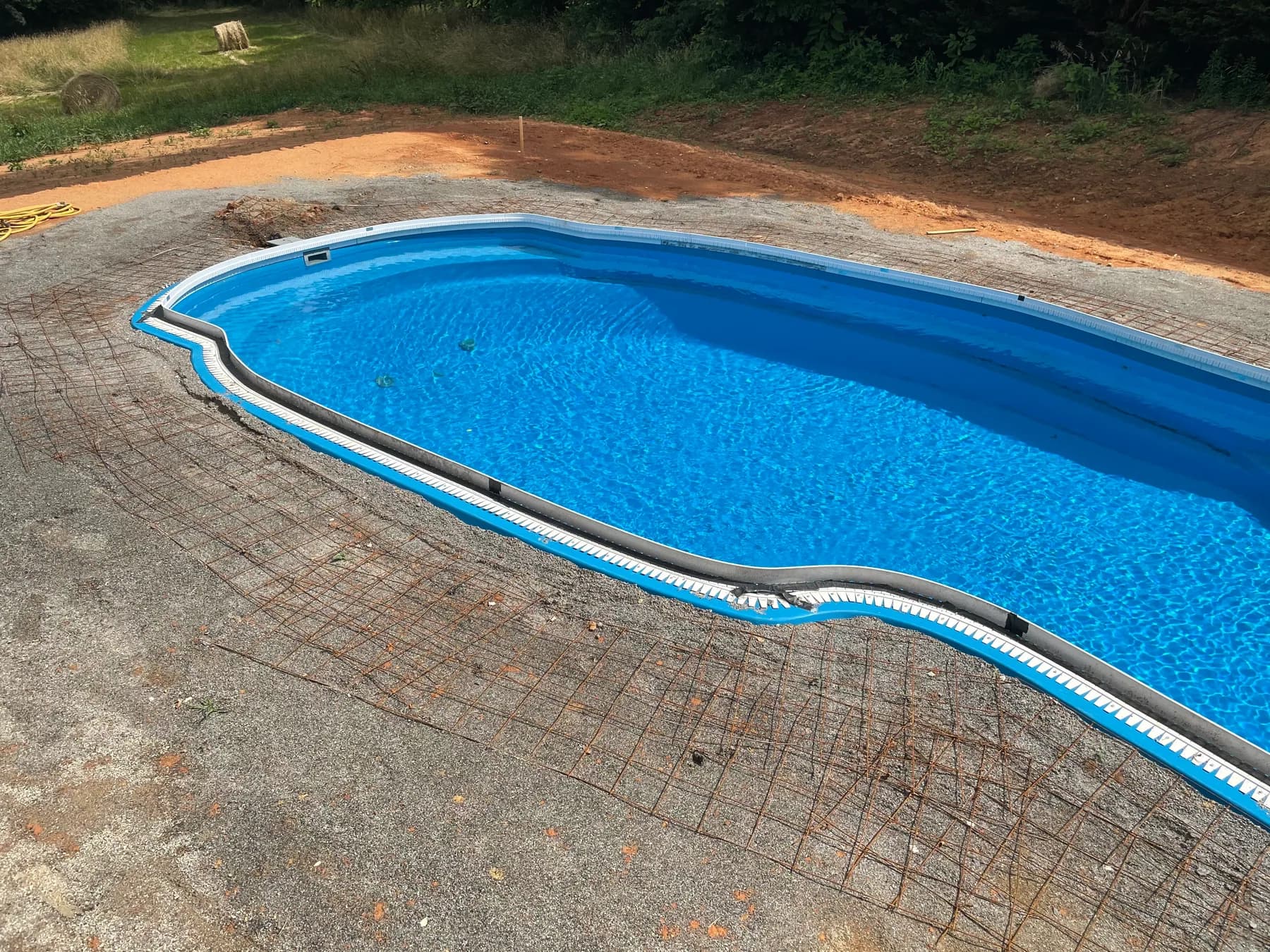 Poolside paver deck installation with border course and curved pool edge, view 2