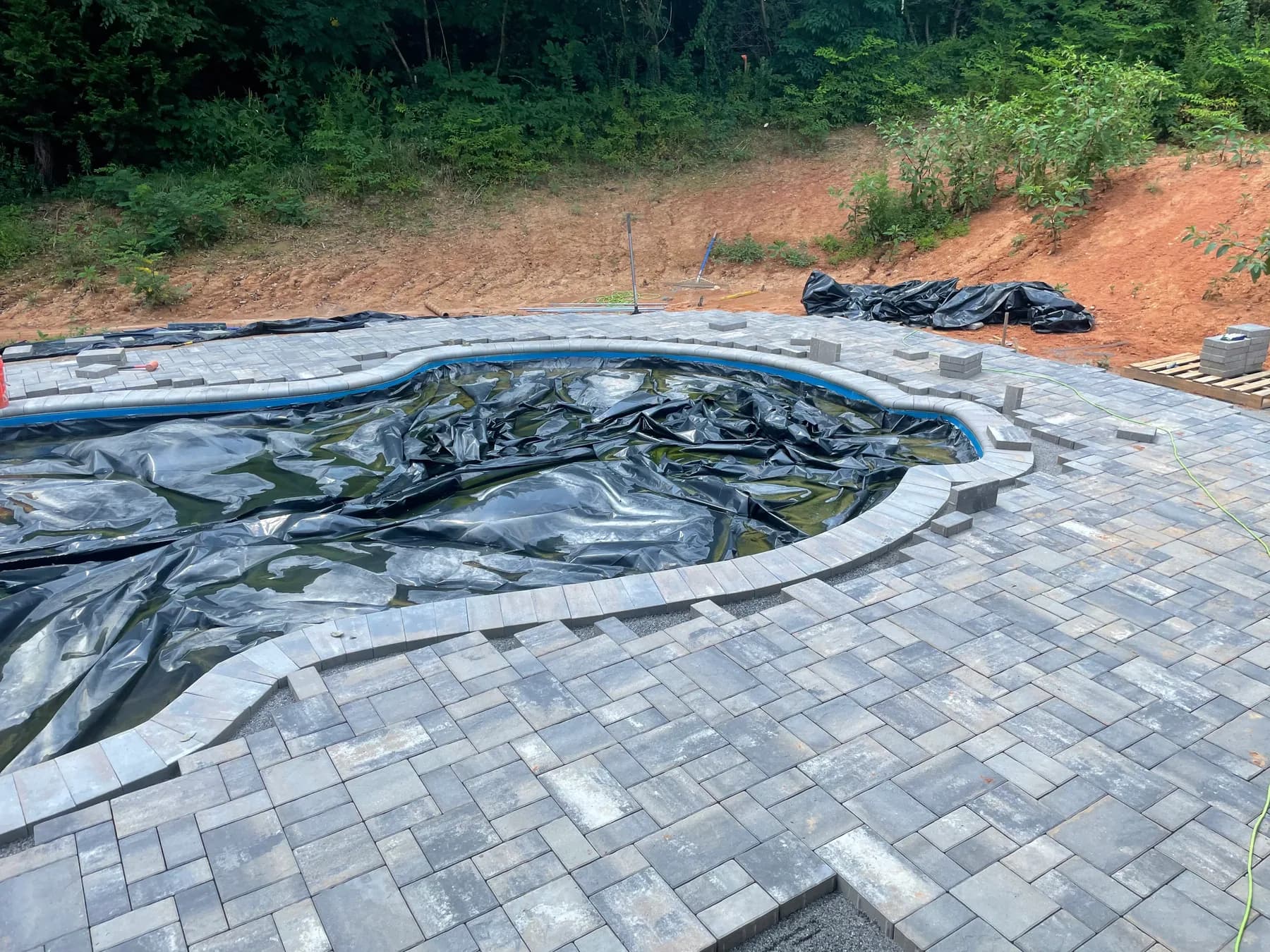Poolside paver deck installation with border course and curved pool edge, view 6