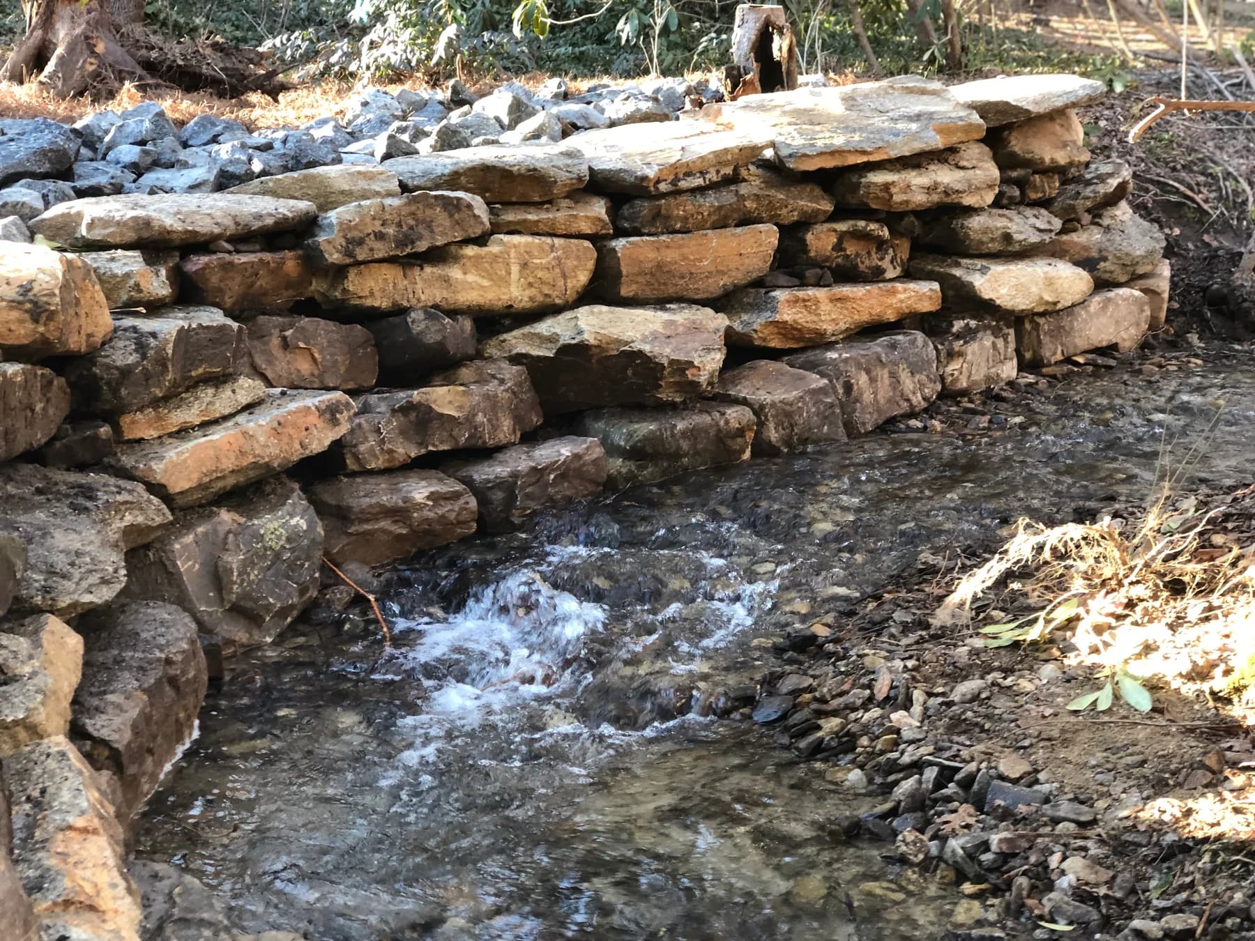 Stacked stone riverbank stabilization detail at the waterline, view 3