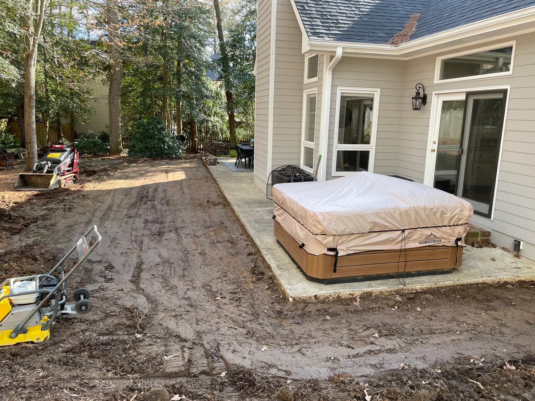 Cleared backyard patio area beside the house before paver base work