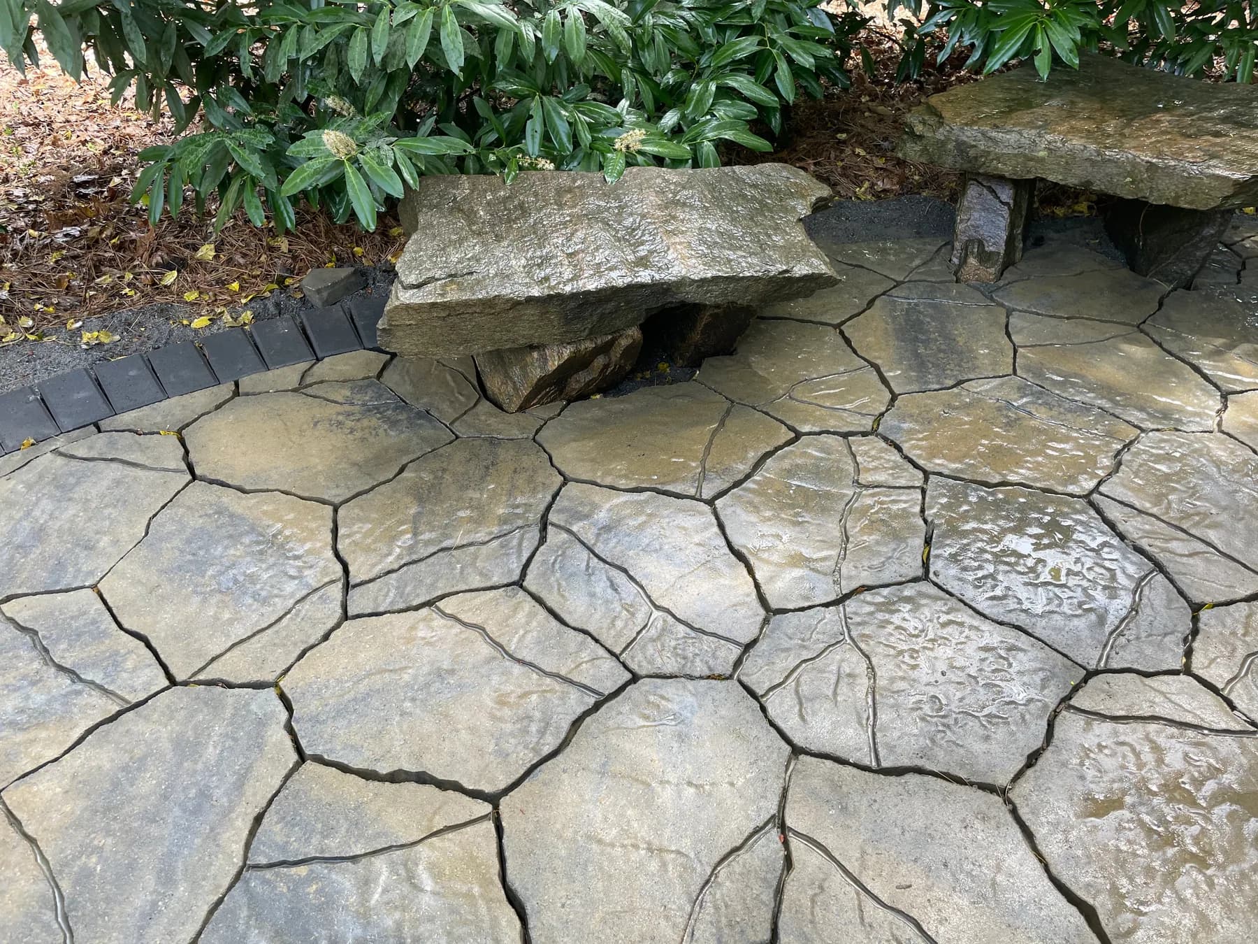 Woodland paver patio with natural stone seating tucked into a wooded edge